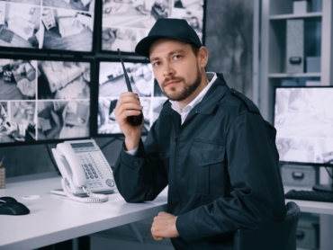 male security guard using radio transmitter surveillance room min