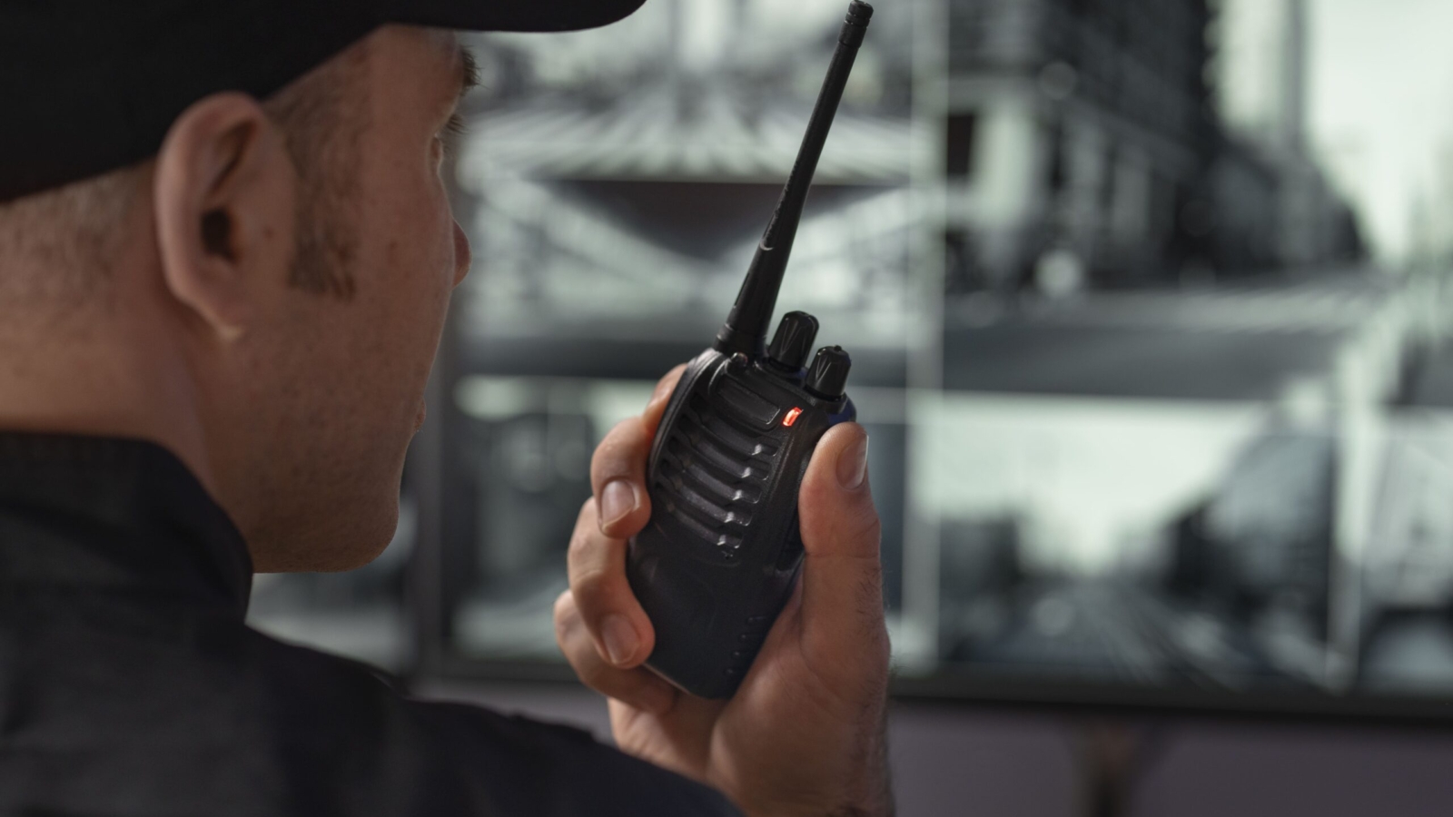 portrait male security guard with radio station camera screens min